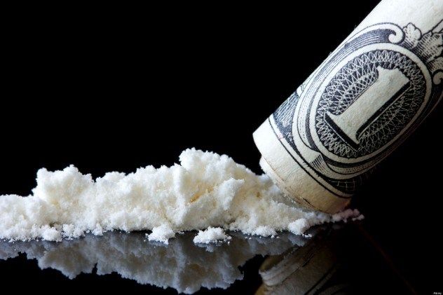 Rolled-up dollar bill sliding across a mirror filled with cocaine symbolizing the need to hire a qualified Houston Criminal Lawyer